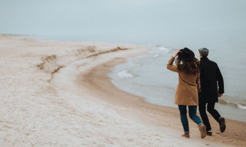 Couple walking on a quiet beach on a cold winter day