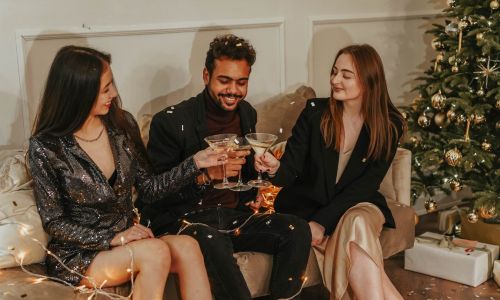Friends toasting with champagne next to a Christmas tree on New Year's Eve