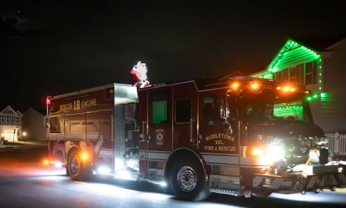 Fire truck decorated with Christmas lights in a holiday parade at night