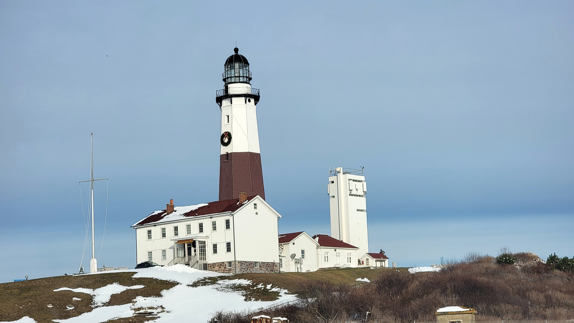 Montauk Point Lighthouse with its holiday wreath and snow on the bluff on December 31