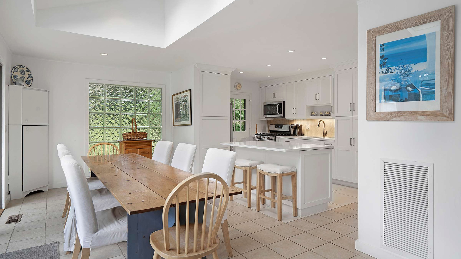 Farmhouse dining table and white kitchen at the Southampton / Shinnecock Retreat in Southampton, NY