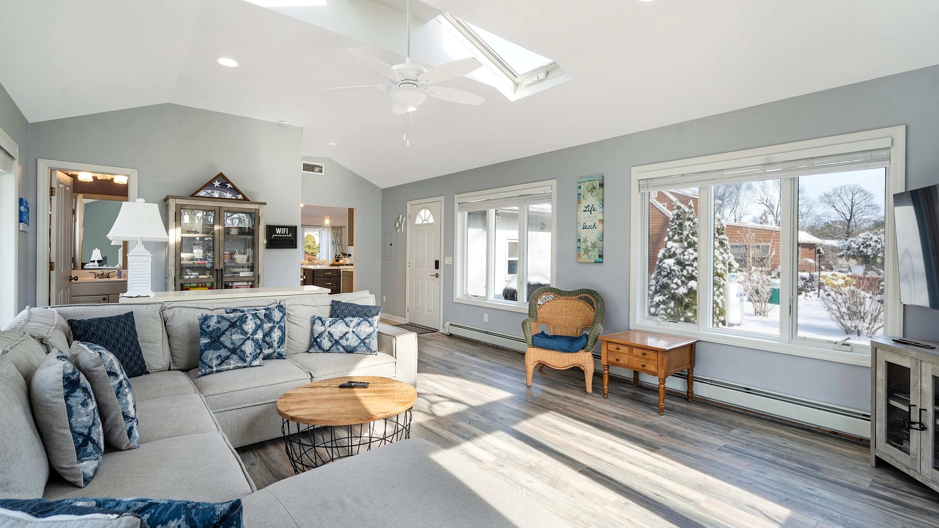 Sunny living room with a snowy winter view at Poppy's Hampton House in Hampton Bays, NY