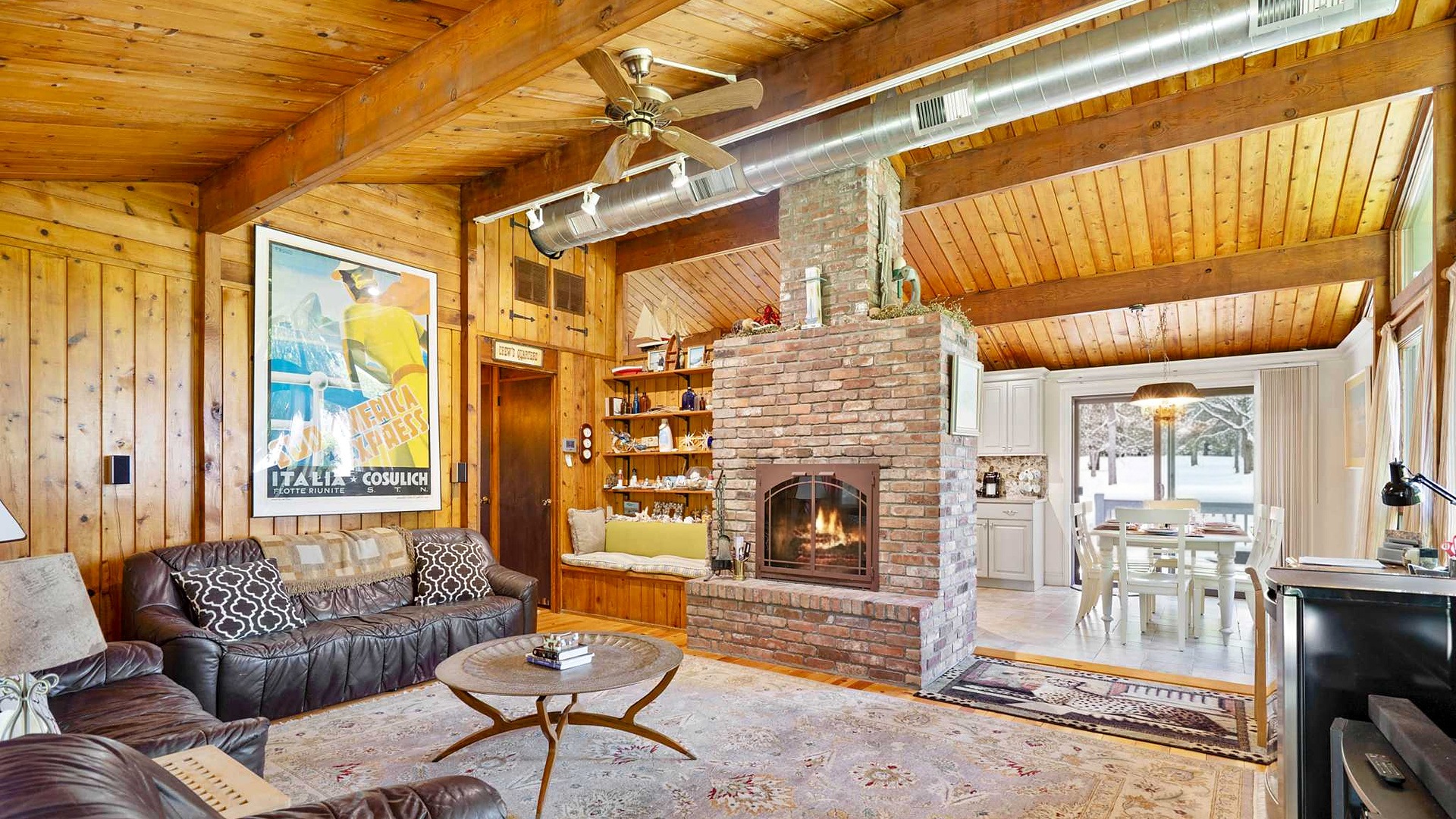 Fire in the brick wood-burning fireplace under wood-plank ceilings at the East Marion 3BR on the North Fork