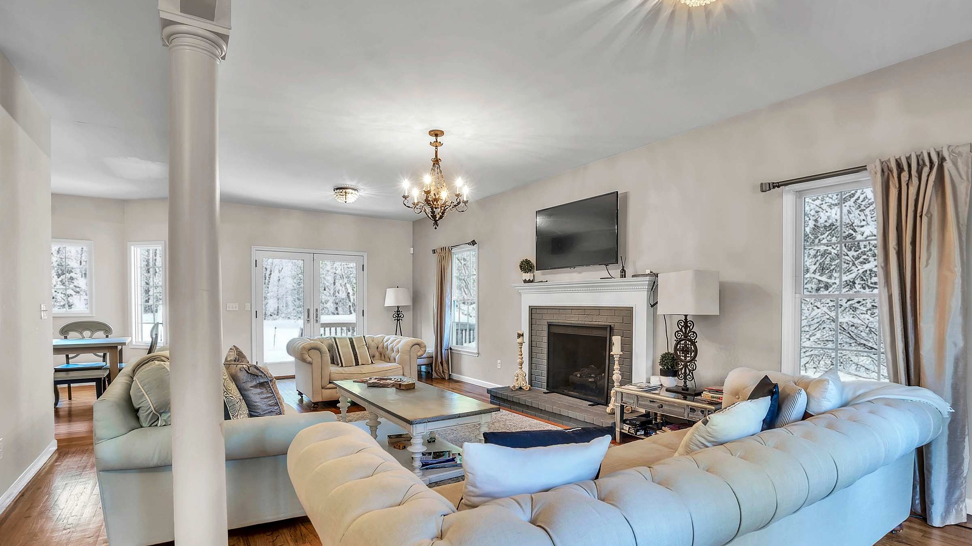 Living room with a fireplace and snowy trees outside at North Fork Oasis, a Luxury Beach Getaway home in Southold, NY