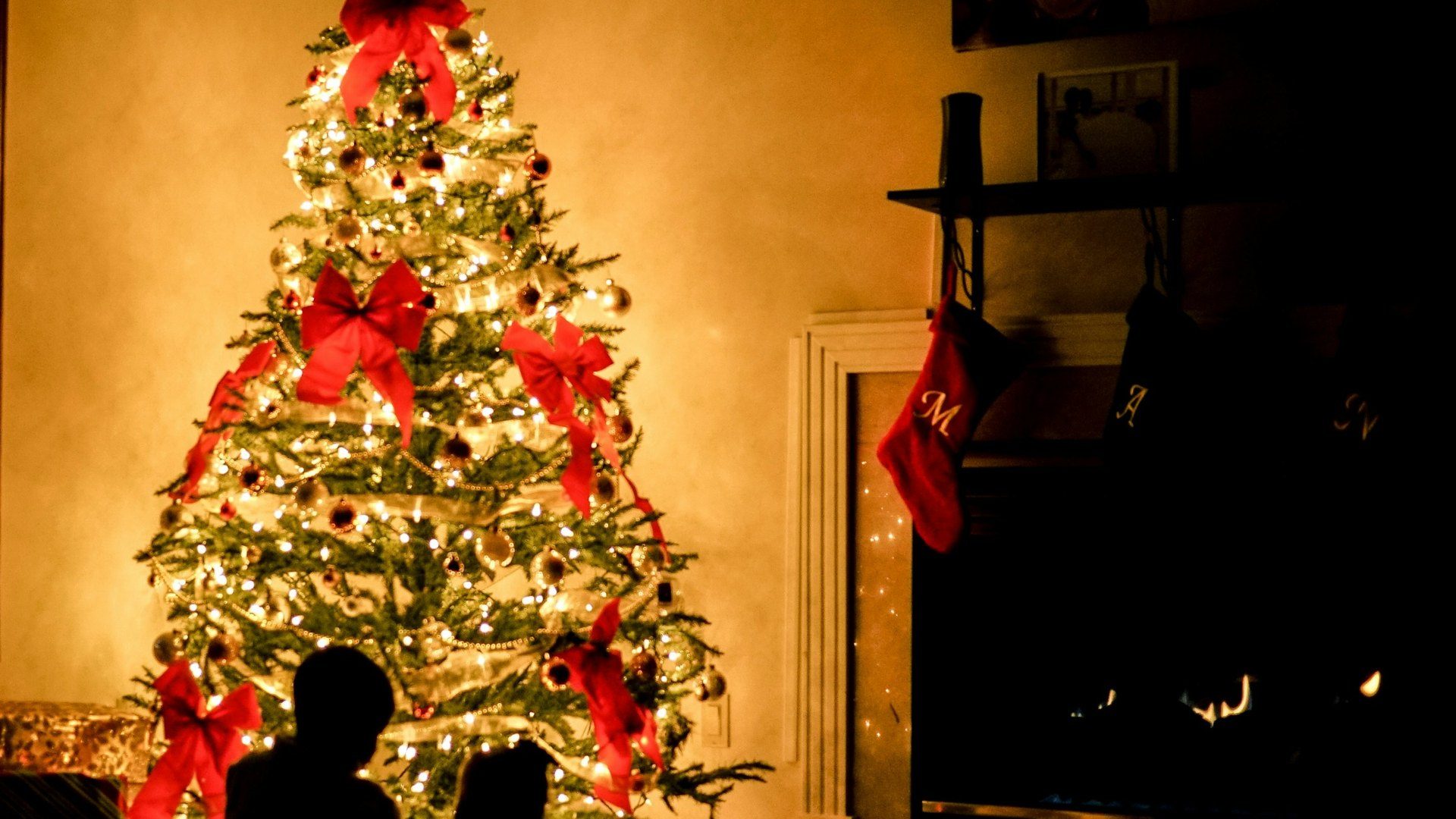 Family sitting by a glowing Christmas tree next to the fireplace