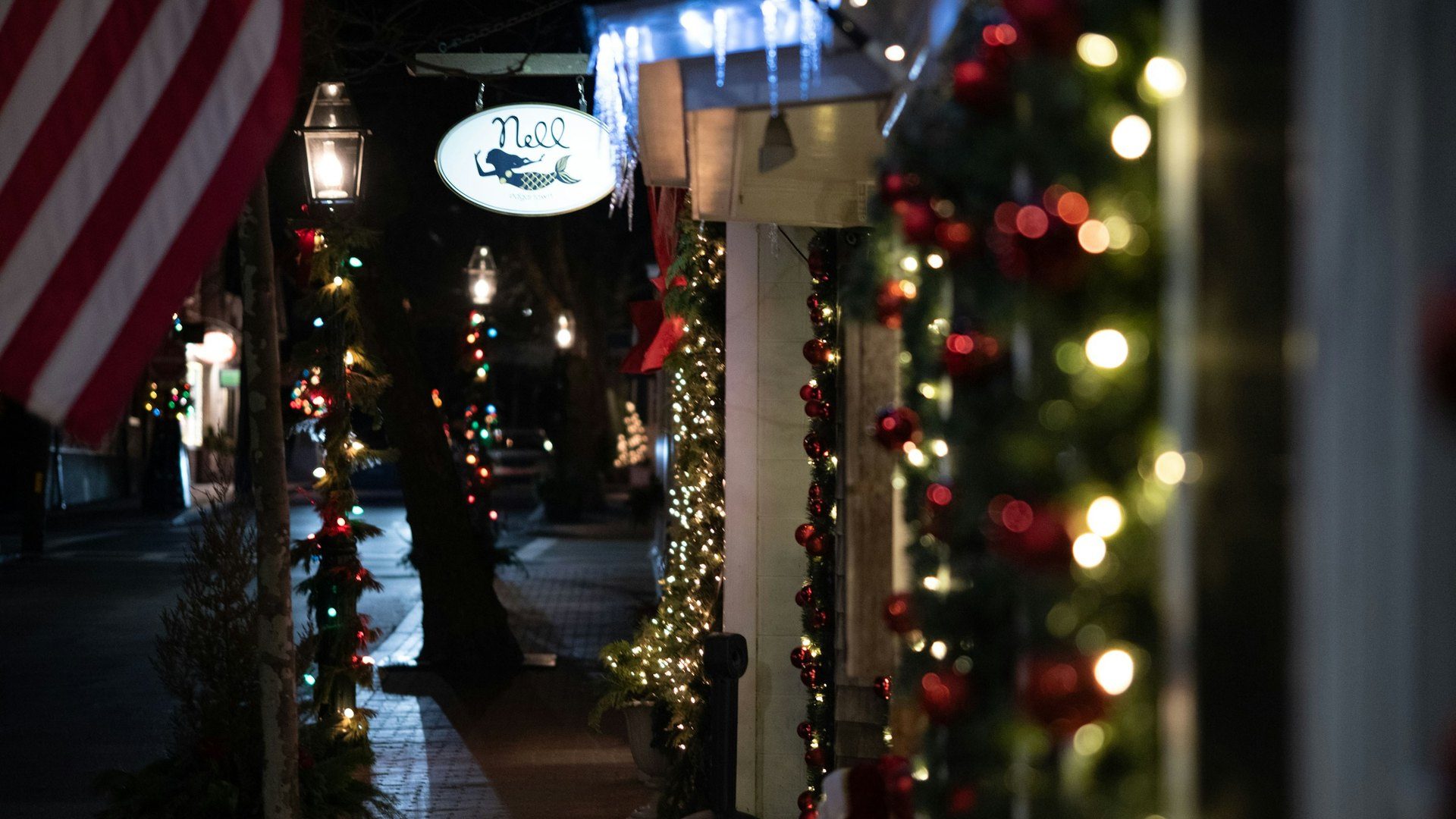 Small-town street at night with Christmas garlands and lights on the storefronts