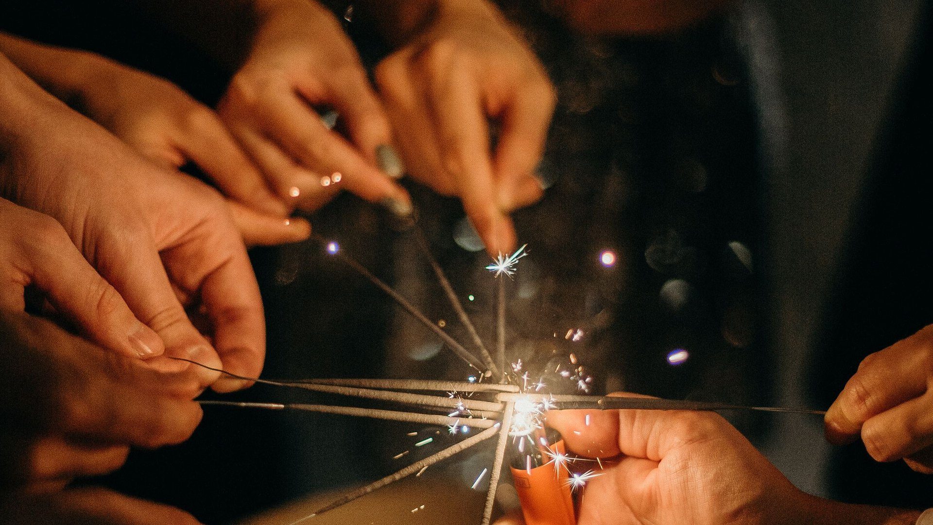 Group of friends lighting sparklers together at a New Year's Eve celebration