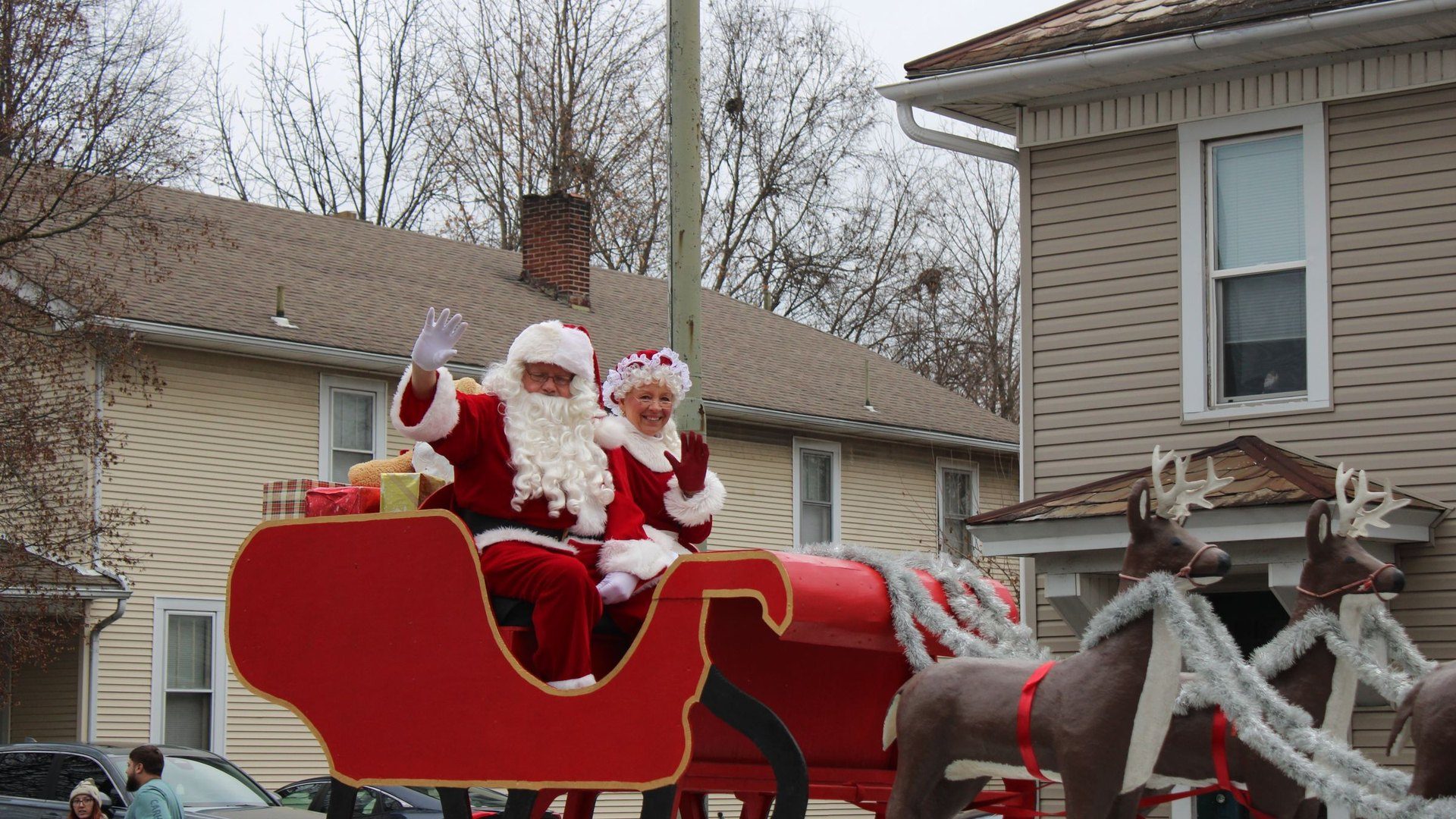 Santa and Mrs. Claus waving from a sleigh during a holiday parade